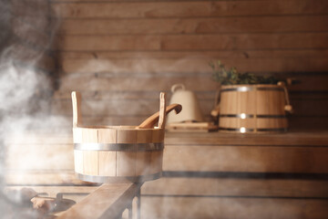 Bucket, ladle and other bath supplies surrounded by steam in sauna