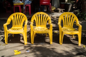 Three bright yellow plastic chairs outdoors