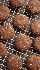 Top view of gluten free crunchy chocolate mixed nuts cookies, on a wire rack, over black marbled background. 