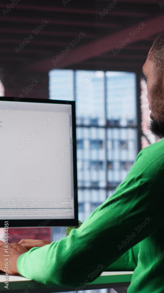 Fototapete Vertical Video Black IT expert looking at user interface on computer at home office, typing and programming code on terminal window. Coding application used by technician writing script in loft