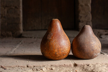 Two rustic dried calabash gourds standing on an old stone floor in a traditional Guatemalan home....