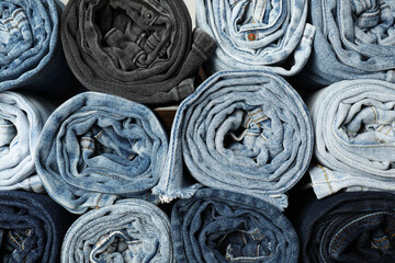 Different stylish rolled jeans as background, top view