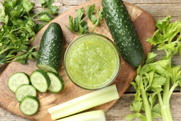 Healthy parsley smoothie in glass, leaves, cucumber and celery on wooden table, flat lay