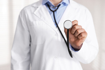 Doctor with stethoscope on light background, closeup