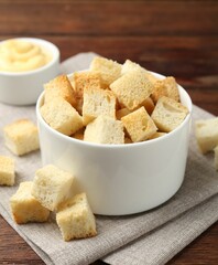Delicious crispy croutons with sauce on wooden table, closeup