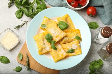Delicious ravioli with cheese and basil served on grey table, flat lay