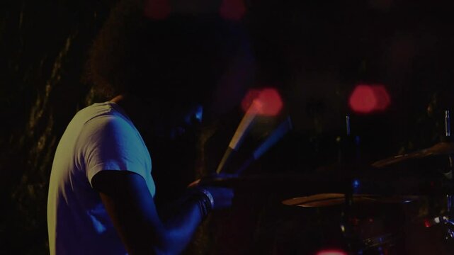 drummer performing music on drum kit under blue red lights, showcasing rhythmic motion graphics