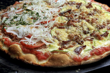 Brazilian pizza with half with meat, cheese, onions and tomatoes and the other half with cheese and bacon