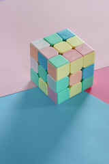 Pastel pink, blue and green papers, and a puzzle cube