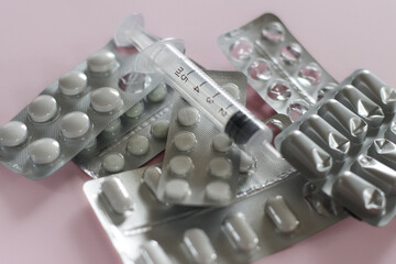 Close-up shot of different drugs and medicine on a pastel pink background.
