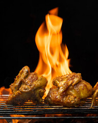 Two pieces of chicken are on a grill, with flames behind them