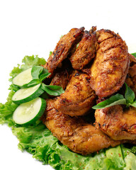A plate of chicken wings is topped with cucumber and lettuce