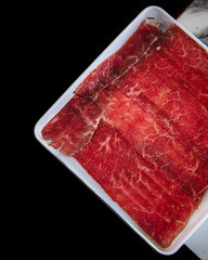 A slab of red meat is sliced into thin strips
