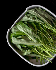 A white bowl filled with green leaves