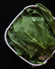 A white bowl filled with green spinach leaves