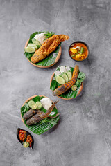 A plate of food with a variety of dishes including fried fish, vegetables