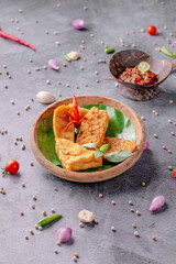 A bowl of food with a green leaf on top and a bowl of sauce next to it