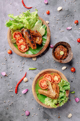 Two plates of food with chicken and tomatoes on a green leaf