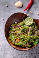 A bowl of food with a green color and a wooden bowl