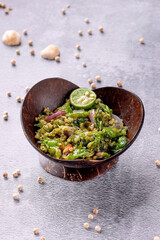 A bowl of food with a green color and a lime in it
