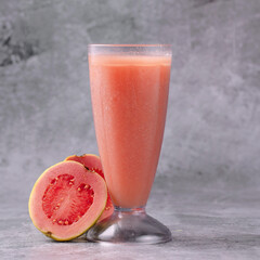 A glass of pink juice with a slice of tomato on the side