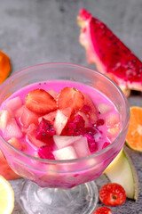 A glass bowl filled with pink fruit juice and strawberries