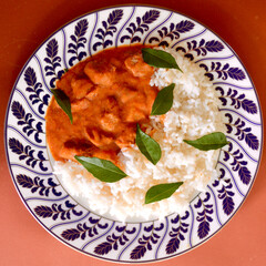 A closeup of Massaman beef curry with jasmine rice and garnished with curry leaves. 