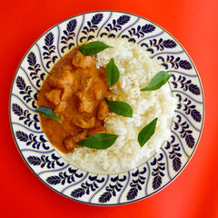 A closeup of Massaman beef curry with jasmine rice and garnished with curry leaves. 