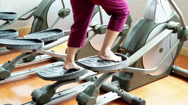 Slow motion video showing exercise pattern on elliptical in gym.