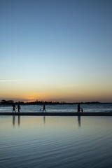Obraz premium Silhouettes of children playing on the beach at sunset.