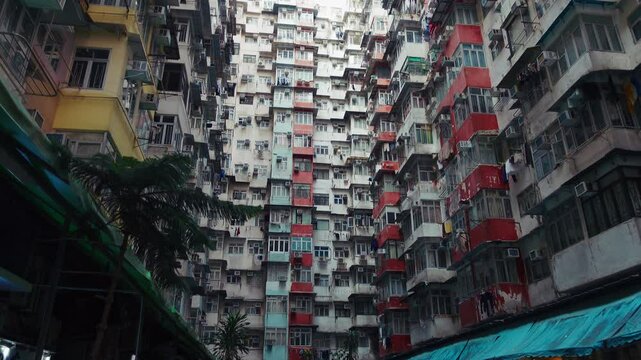 Unique architectural view of Hong Kong Monster Building, a dense residential complex featuring colorful, stacked apartments. The video captures the intricate fasade and bustling atmosphere