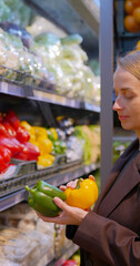 Woman choosing and smells red bell pepper while selecting vegetables