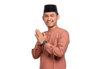 Smiling young Asian Muslim man gesturing Eid Mubarak greeting isolated on transparent background