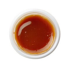 a small. round container filled with a thick. amber-colored substance. likely a type of syrup or sauce the glossy surface reflects light. indicating a viscous texture this could be used in cooking or