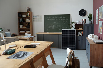 Room equipped for modern education featuring various technological devices and learning materials. Chalkboard and cabinets filled with books and tools surrounding the room