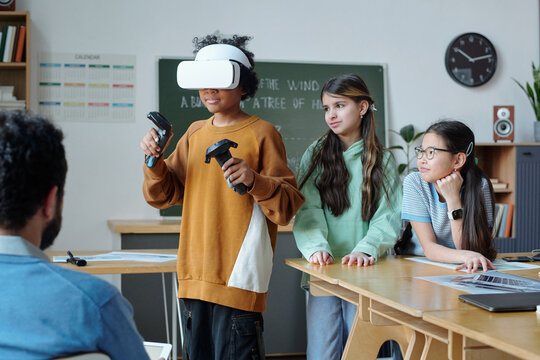 Students in classroom setting engaging with virtual reality technology, with one student wearing VR headset while others observing