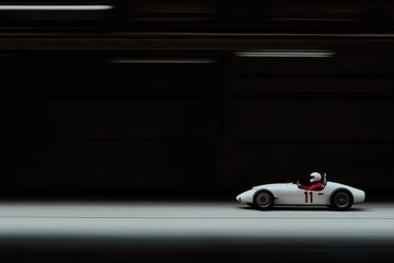 Fototapeta premium 暗いトンネルの中を白いレーシングカーが高速で走り抜ける瞬間が捉えられている。