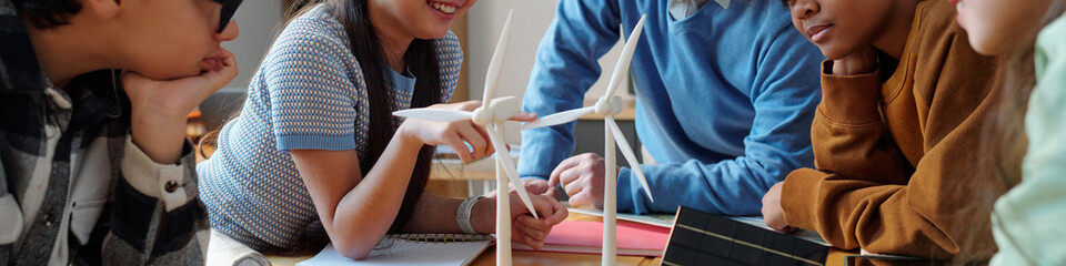 Group of diverse students collaborating on a science project, discussing and setting up a wind...