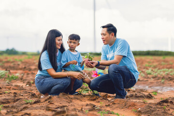 family of three, a man and two children, are planting a tree together