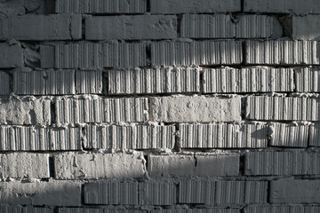 Fragment of brickwork, close-up. Brick wall, close-up. Potholes and defects in a brick wall, flat layout. Cracks and defects in bricks on a wall, color fantasy.
