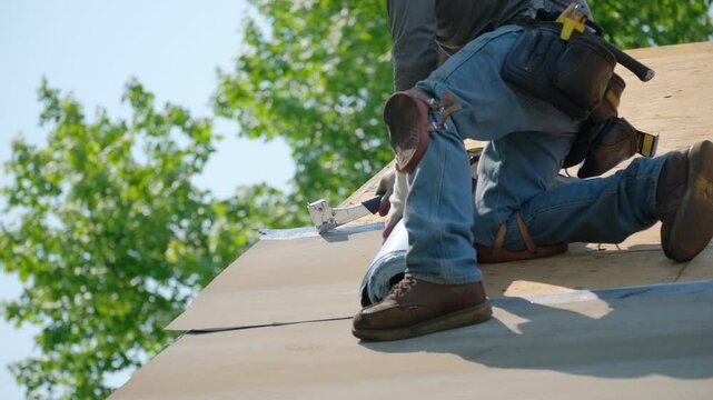 Roofer installing a new roof covering with glue surface. Self-Adhering Roofing System process.