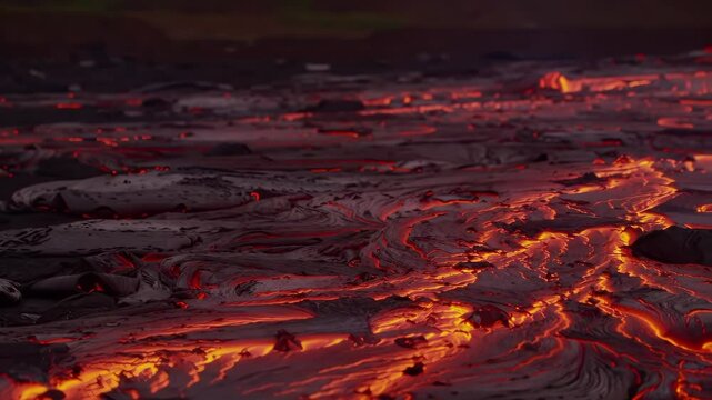 Red hot volcanic lava stream flowing and cooling at night. Natural earth power concept background footage.