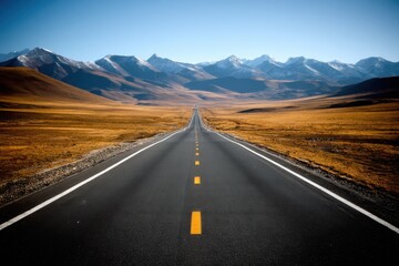 Naklejka premium Serene Road Journey Through Golden Fields Leading to Majestic Snow Capped Mountains Under Clear Blue Sky Capturing the Essence of Travel and Adventure