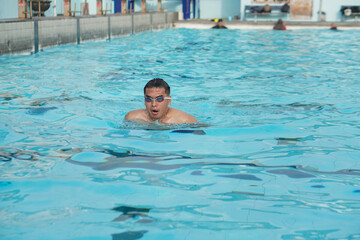 Asian man swimming in public pool