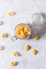 Raw uncooked dried Conchiglie shell pasta. Italian seashells pasta in lock lid jar on white background.