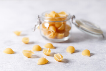 Raw uncooked dried Conchiglie shell pasta. Italian seashells pasta in lock lid jar on white...