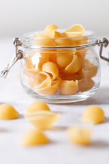 Raw uncooked dried Conchiglie shell pasta. Italian seashells pasta in lock lid jar on white background.