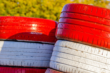 Stacked colorful rubber tires waiting for use near a workshop in the afternoon sunlight