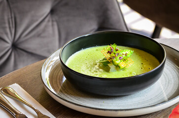 Green asparagus soup elegantly served in a restaurant setting. Modern food presentation.