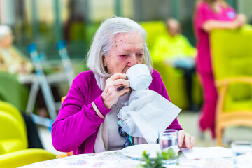 Elderly woman drinking tea in nursing home care facility
